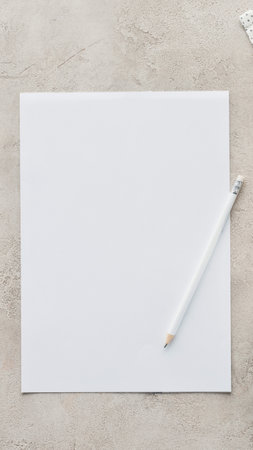 A clean white sheet of paper lies on a speckled surface with a white stylus pen resting on its corner.の写真素材