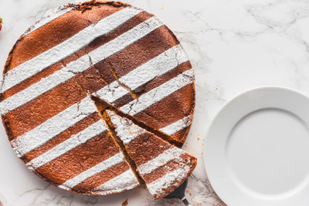 A round chocolate cake with a striking white striped pattern, partially sliced and ready to be served on a white plate.の写真素材