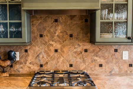 A detailed view of a gas stove in a kitchen, featuring a striking marble backsplash and two windows above.の写真素材
