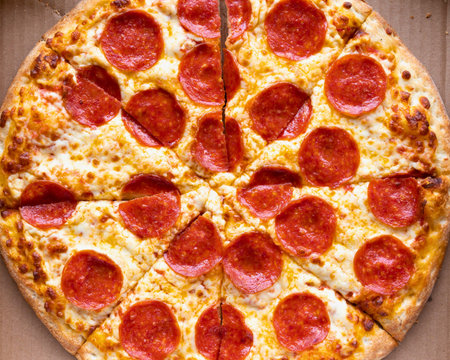 A close-up, overhead view of a freshly baked pepperoni pizza, showcasing its crispy crust, melted cheese, and savory toppings.の写真素材