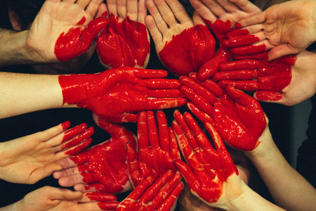 A collection of hands, painted bright red, are arranged to create the shape of a heart, symbolizing unity and love.の写真素材