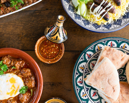 A vibrant overhead view of a table laden with various Middle Eastern dishes, including a hearty stew, fresh salad, and warm pita bread.の写真素材
