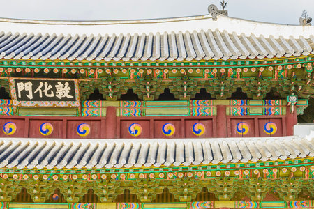 A close-up view of a traditional Korean palace building, showcasing its colorful tiled roof, decorative eaves, and ornate architectural elements.の写真素材