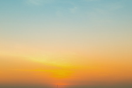 A pixelated abstract representation of a sunset with gradients of warm orange, yellow, and soft blue in the sky.の写真素材