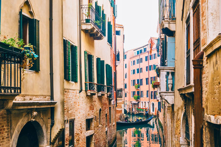 A picturesque canal in Venice, Italy, with reflections of colorful buildings and ornate balconies, creating a charming and historic atmosphere.の写真素材