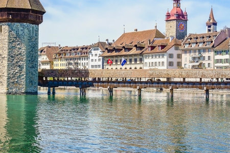 A picturesque view of an ancient covered wooden bridge and traditional European buildings reflected in a calm river.の写真素材