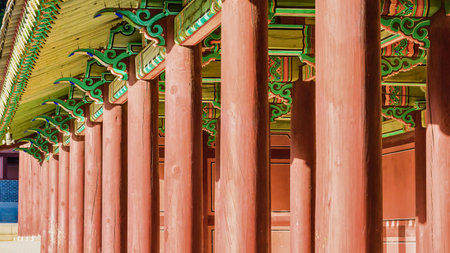 A repeating pattern of vibrant red pillars leads the eye towards intricately decorated eaves of a traditional building.の写真素材