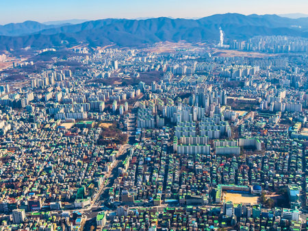 An overwhelming expanse of urban development stretches towards distant, hazy mountains under a clear sky.の写真素材