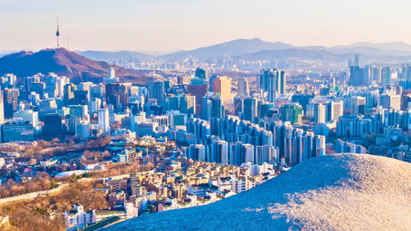 A sprawling urban landscape filled with tall buildings and a distant mountain range under a clear sky.の写真素材