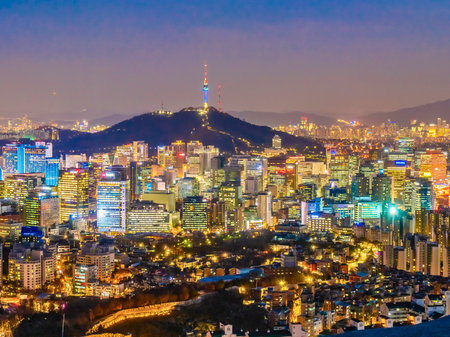 A sprawling urban panorama of Seoul at twilight, illuminated by countless city lights and dominated by Namsan Tower atop its hill.の写真素材