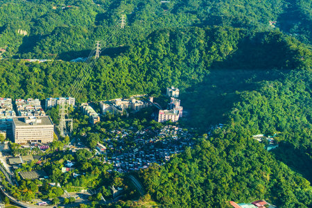 An aerial perspective showcases dense green trees bordering a cluster of buildings and roads, hinting at urban development within a natural landscape.の写真素材