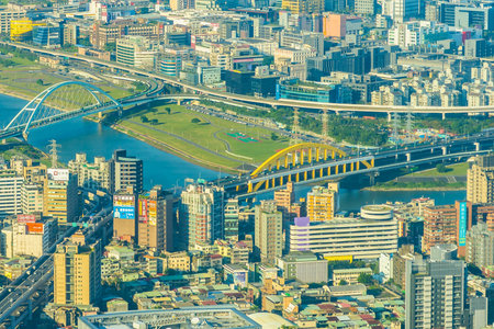 An elevated perspective showcases a dense urban environment with numerous skyscrapers, a winding river, and a prominent bridge connecting city sections.の写真素材