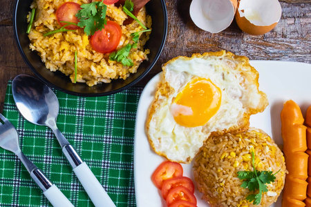 A delicious and filling breakfast spread featuring a sunny-side-up egg, crispy sausages, and a generous portion of noodles.の写真素材