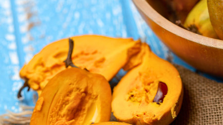 Close-up of vibrant orange pumpkin halves and slices on a textured blue wooden surface with burlap fabric.の写真素材