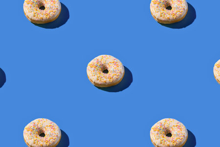 A top-down view of multiple round rings, casting shadows, arranged in a grid on a vibrant blue surface.の写真素材