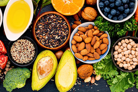 A colorful overhead view of various nutritious foods including fruits, vegetables, nuts, seeds, and grains, arranged artfully.の写真素材