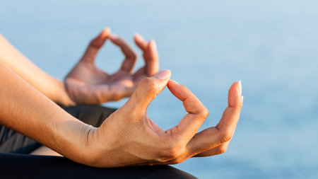 A serene close-up shows hands performing the Gyan Mudra, a gesture of knowledge and wisdom, against a soft blue background.の写真素材