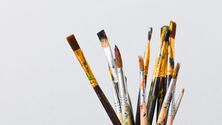 A close-up shot showcases a variety of paint brushes with different bristle types and handle colors against a plain white backdrop.の写真素材