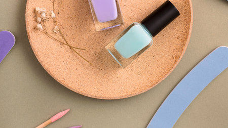 Several bottles of pastel colored nail polish are artfully arranged on a textured, oval-shaped tray with a subtle floral design.の写真素材