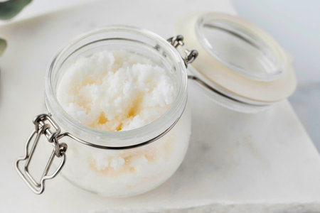 A clear glass jar with a hinged lid filled with fluffy white whipped body butter, perfect for moisturizing skin.の写真素材