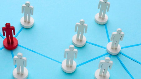 A single red figure stands out among a group of white figures connected by blue lines, symbolizing connection and individuality.の写真素材