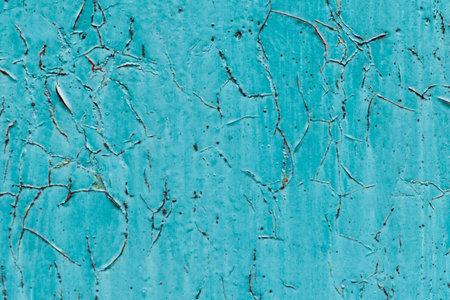A close-up view of a textured teal blue surface with visible cracks and peeling paint, suggesting age and wear.の写真素材