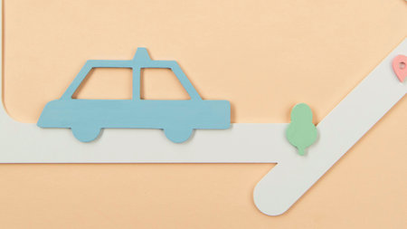 A minimalist, flat illustration of a blue car on a white paper road with a small green tree against a peach background.の写真素材