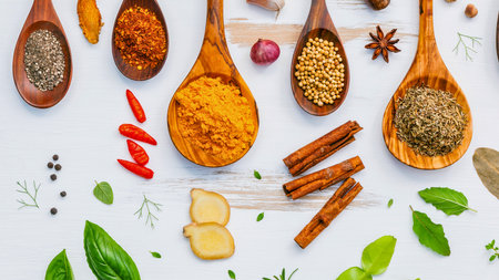 A vibrant collection of various spices and fresh herbs arranged on a white surface, showcasing culinary ingredients.の写真素材