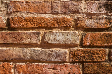 A detailed, close-up view of an old brick wall showing varied textures, colors, and imperfections in the masonry.の写真素材