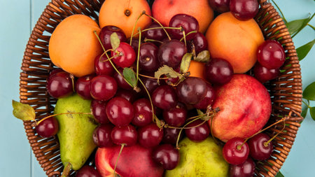 A woven basket overflows with ripe cherries, apricots, plums, and pears, showcasing a vibrant assortment of summer's bounty.の写真素材