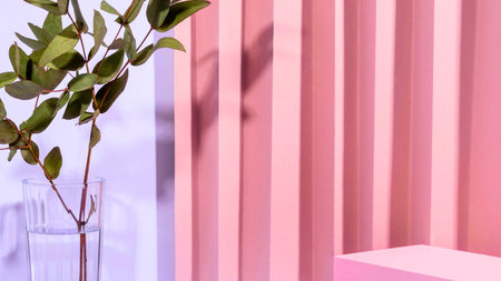 A delicate green plant stem with leaves is positioned against a soft pink background featuring vertical ribbed texture and a subtle shadow.の写真素材