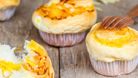 Close-up of freshly baked sweet buns with golden toppings and a hint of chocolate, presented on a...