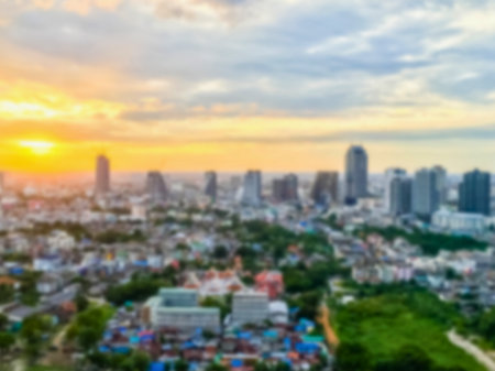 An aerial view of a sprawling city skyline bathed in the warm glow of a sunset, with scattered clouds in the sky.の写真素材