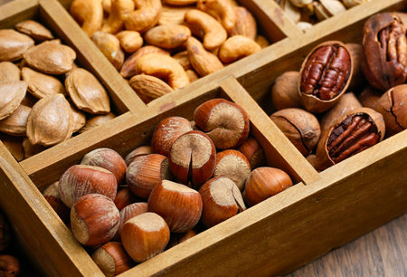 A close-up view of a wooden box filled with various types of nuts and seeds, showcasing their textures and colors.の写真素材