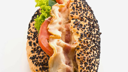 A close-up shot of a gourmet hot dog bun filled with savory meat, crisp lettuce, and juicy tomato...