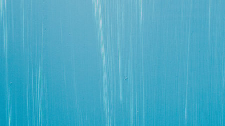 A soft, textured blue background with subtle vertical streaks of lighter blue and white, creating an abstract, serene visual.の写真素材