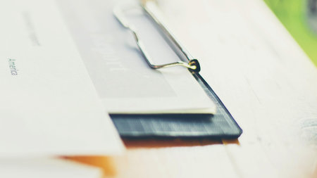 A shallow depth of field shot shows a clipboard with papers and a pen, suggesting a work or study...