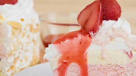 A vibrant red strawberry with glossy syrup cascades over a soft, white dessert, creating a tempting sweet treat.の写真素材