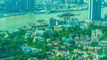 An elevated perspective showcases a vibrant city where dense greenery intertwines with urban structures and a flowing river.の写真素材