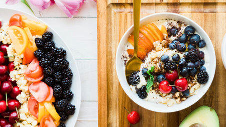 A vibrant and delicious breakfast featuring a bowl of oatmeal topped with fresh berries, sliced fruit, and a side of colorful fruit skewers.の写真素材