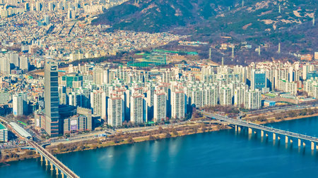 An expansive aerial view showcases the Han River flowing through Seoul, South Korea, flanked by numerous high-rise buildings and bridges.の写真素材
