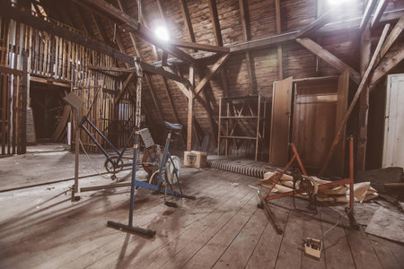 A dog jumping over a hurdle inside a barn or farm building with wooden walls.