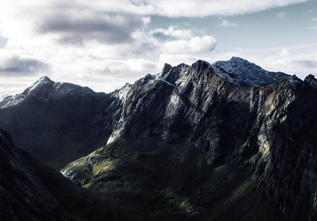 A stunning mountain landscape featuring a tall rocky peak under cloudy skies.