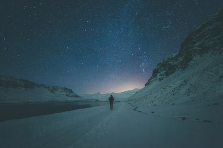 A person in a mountain valley at night with stars shining bright overhead.
