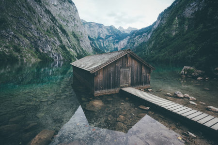 A wooden bridge spans over a calm mountain river in a scenic canyon with rocky cliffs and lush trees.
