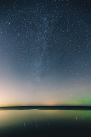 A peaceful scene showing stars in the night sky with a sunset over a quiet landscape.