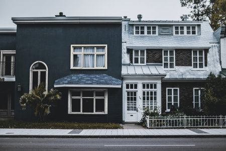 A black and white photo of a two-story house with large windows and front yard.