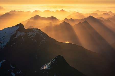 A beautiful sunrise scene showing mountain peaks with fog and clouds in the early morning light, creating a peaceful natural landscape.