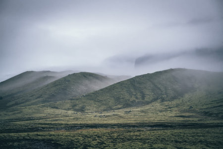 A photo of mountains with cloudy sky and open land.