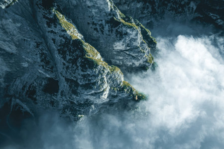 A natural scene of a mountain with fog in a green outdoor setting.